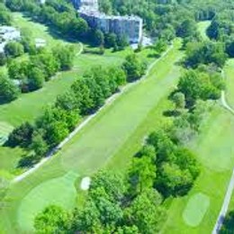 Aerial view of Norbeck Country Club fairways framed by mature trees, with the clubhouse beyond.